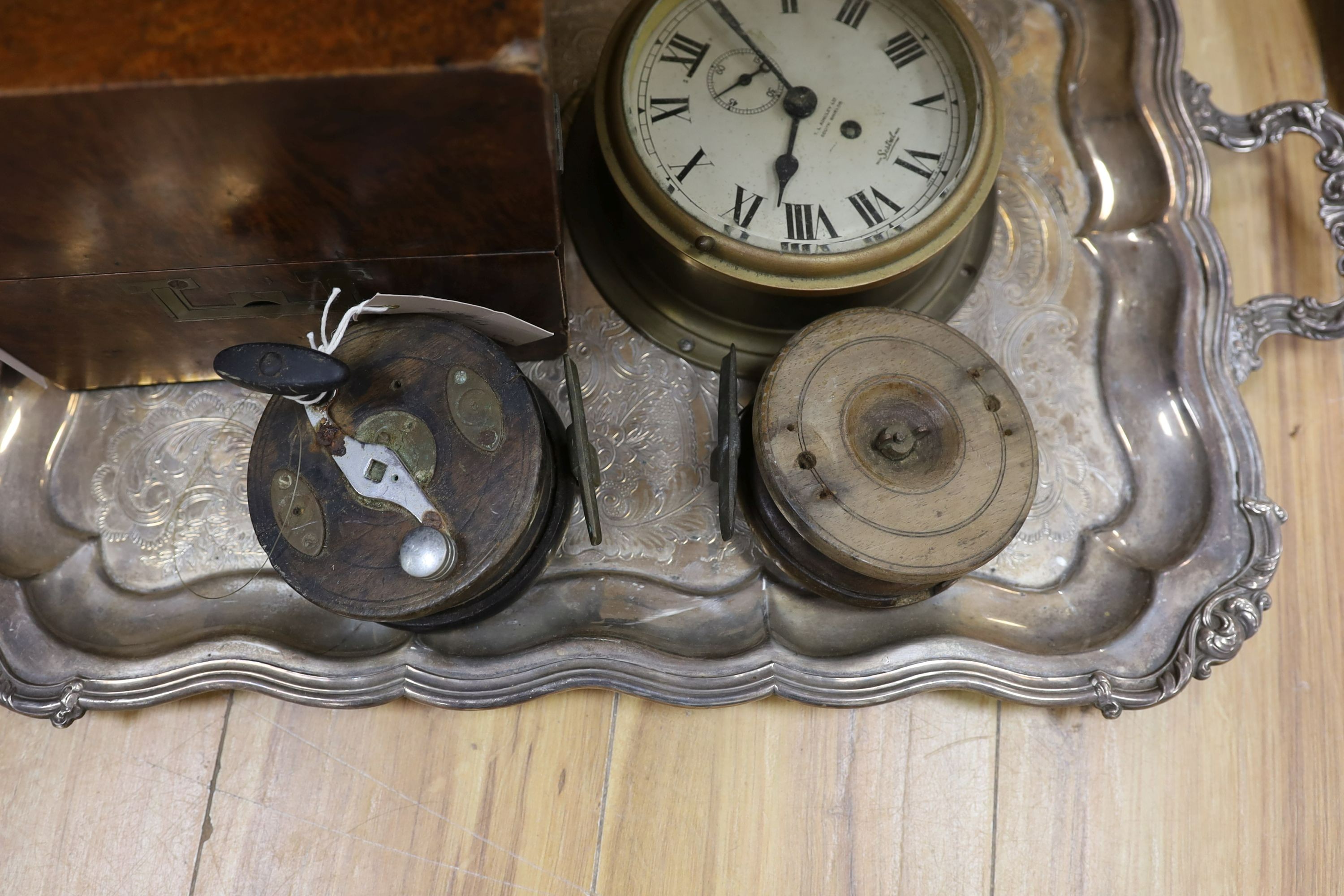 A 19th century amboyna box, 22cm wide, a Sestrel ship's wall clock, no key - 20cm diameter, a large plated two-handled tray - 71cm long, Vintage Ogden Smith fishing reel together with another (5)